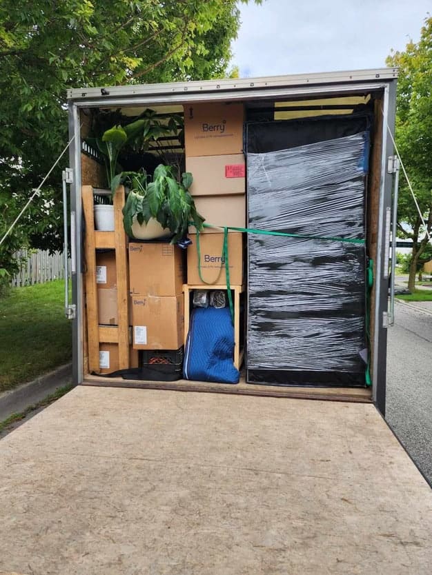 Stacked moving boxes with plants and packing supplies in a storage trailer, professional moving services Bakers Home Solutions.