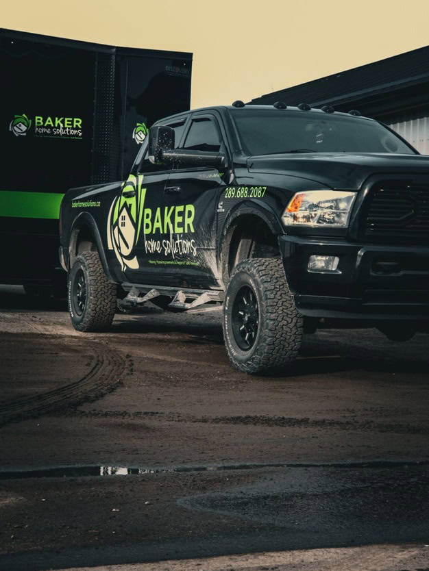 Bakery home solutions truck parked outside on dirt ground.