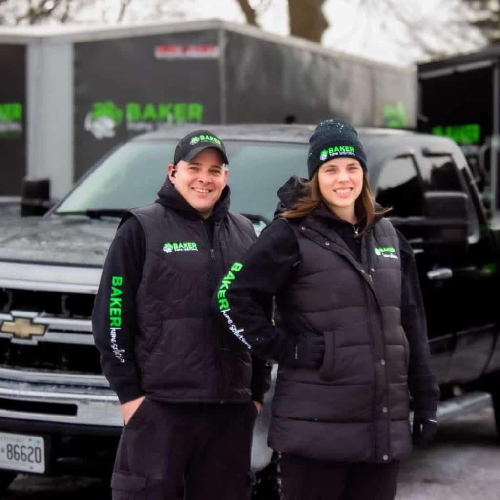 Baker Home Solutions team members standing in front of company trucks with branding.