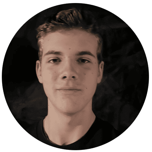 Modern smiling young man with hairstyle and casual attire, indoor setting.