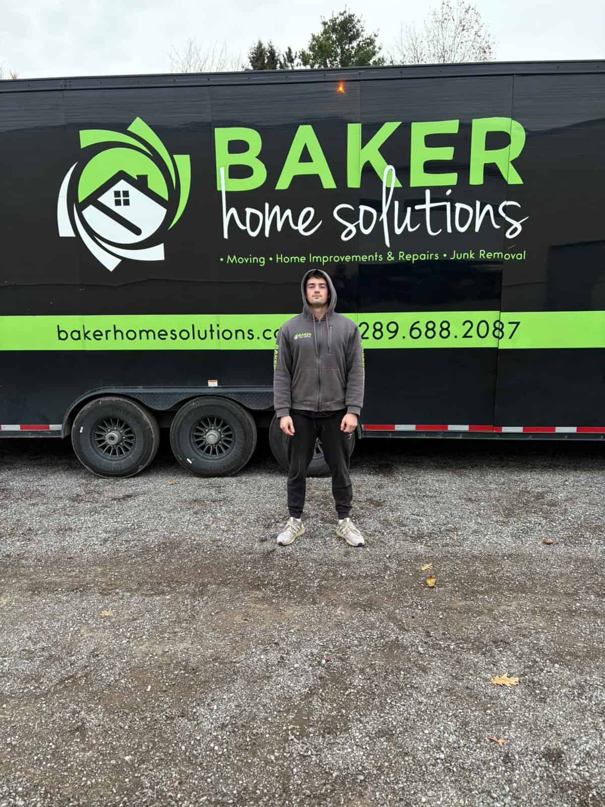 Professional home improvement team with Baker Home Solutions trailer, offering moving, repairs, and junk removal services.