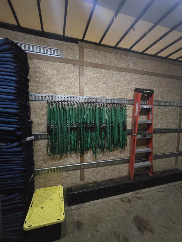 Garage wall storage with hooks, shelves, and ladders for home improvement tools.