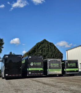 Baker Home Solutions moving trucks on site with a green hedge background, professional home upgrade service.